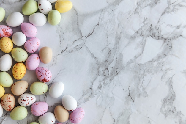 Happy Easter concept. Preparation for holiday. Easter pastel candy chocolate eggs sweets on trendy gray marble background. Simple minimalism flat lay top view copy space.