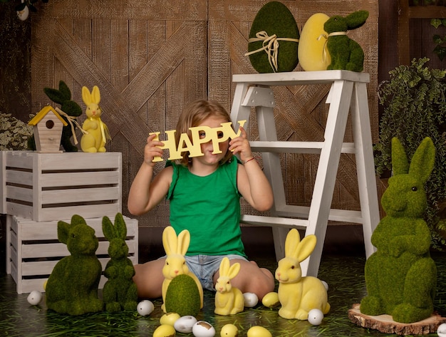 Счастливой Пасхи Милая маленькая девочка, играющая с декоративными зайцами и пасхальными яйцами в комнате, украшенной к Пасхе