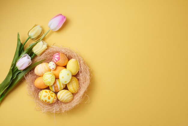 Happy Easter day colorful eggs in nest and flower on paper background with copy space