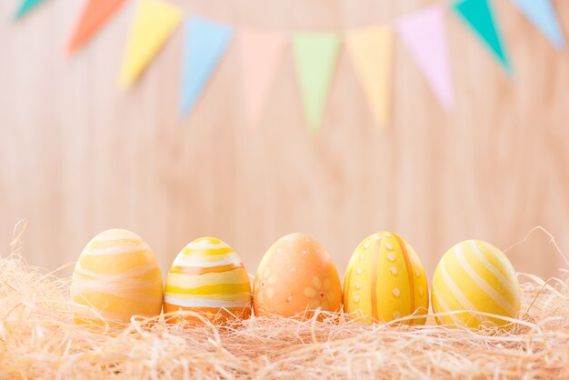 Happy Easter day colorful eggs on nest with blurred celebrate  party flags with copy space