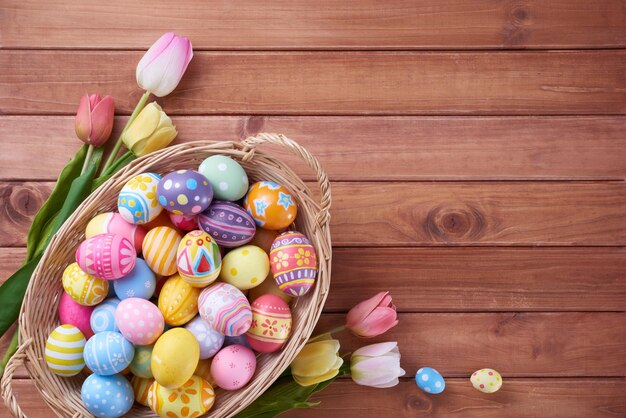 Happy Easter day eggs in basket and flower on wood background with copy space