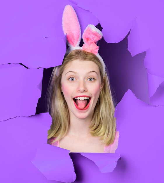 Happy easter day smiling girl in bunny ears looking through paper hole happy woman in rabbit ears