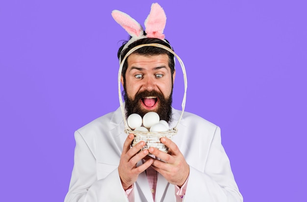 Happy Easter Day. Surprised bearded man with basket egg. Guy in bunny ears. Rabbit man.