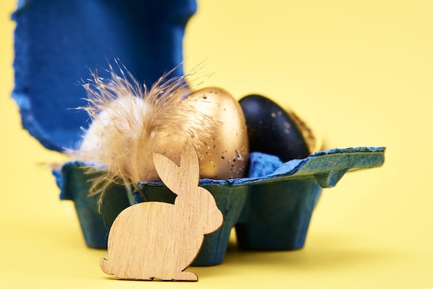 Счастливого пасхального украшения деревянный кролик и яйца на желтом фоне