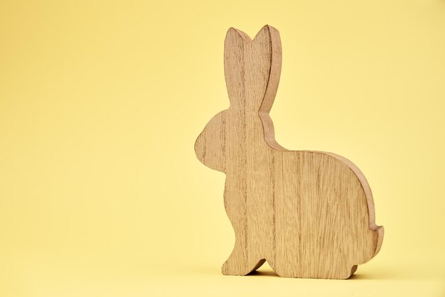 Foto coniglio di legno della decorazione di buona pasqua su fondo giallo