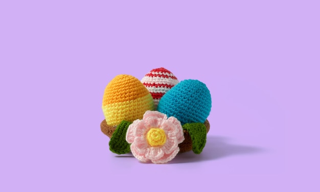 Happy Easter design Nest with eggs and daisies made in crochet and colored wool Violet background