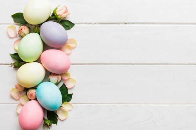 Photo happy easter easter eggs on colored table with yellow roses natural dyed colorful eggs background top view with copy space