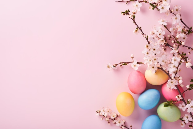 Happy Easter Geverfde paaseieren op rustieke tafel met kersenbloesem boomtak op roze achtergrond Paasvakantie kaart achtergrond met kopie ruimte Bovenaanzicht