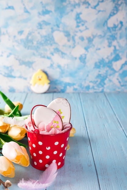 Happy Easter gingerbread cookie eggs with bucket on blue wood background