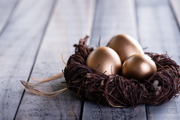 Happy easter! golden of Easter eggs in nest and Feather on wooden background