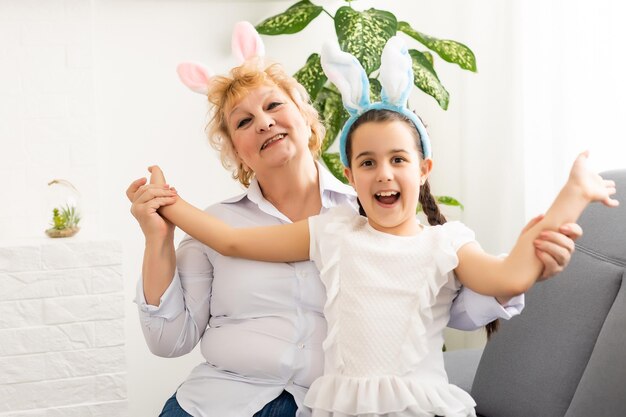행복한 부활절. 부활절 달걀을 그리는 할머니와 손녀. 부활절을 준비하는 행복한 가족. 부활절 날 토끼 귀를 쓰고 있는 귀여운 어린 소녀.