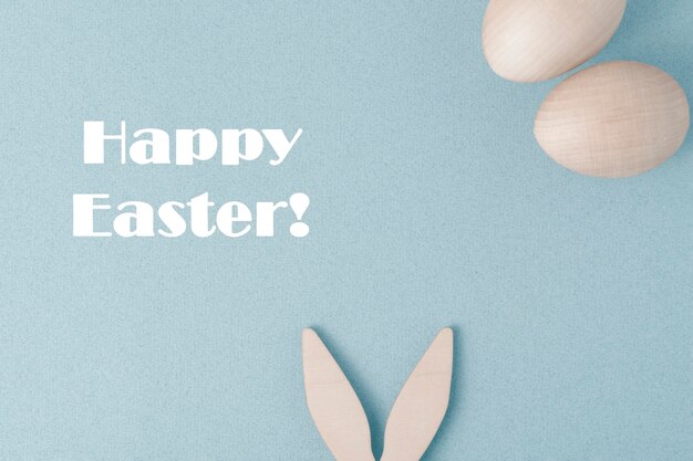 Photo happy easter greeting card. on a blue background, congratulations on easter. the rabbit's ears stick out at the bottom. there are two eggs at the top.