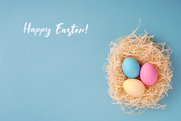 Happy Easter greeting card; Colored eggs in a hen nest.