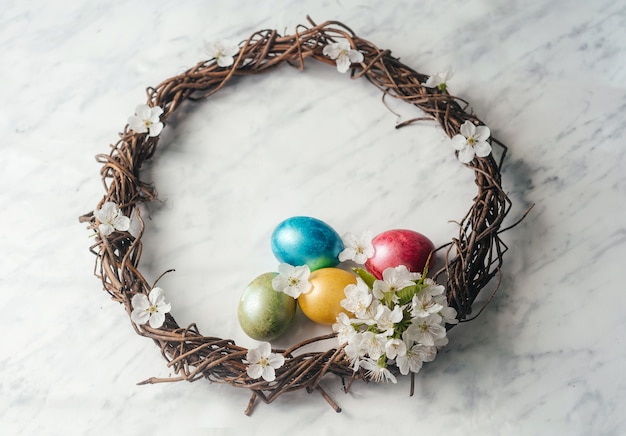 Happy Easter greeting card with Easter wreath, dyed eggs and spring flowers