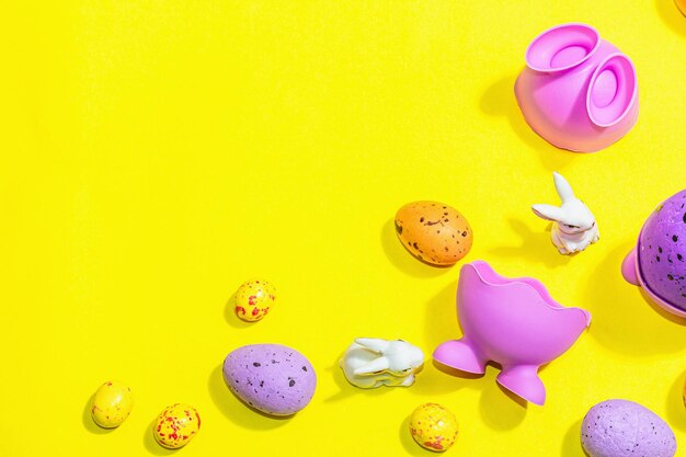 Happy Easter holiday background with eggs cute rabbits and traditional decor Sweet chocolate hard light dark shadow on bright yellow color top view