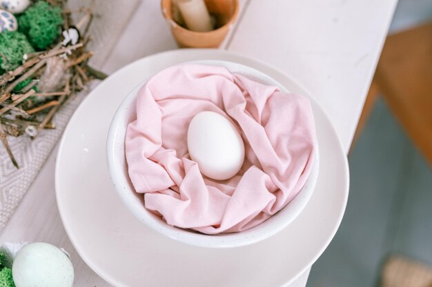 Happy easter holiday in springtime season festive home decor traditional food natural white chicken egg in pastel pink fabric in a plate on the table