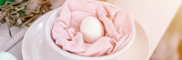 Foto buone vacanze di pasqua nella stagione primaverile festosa decorazioni per la casa cibo tradizionale pollo bianco naturale in tessuto rosa pastello in un piatto sul bagliore della bandiera del tavolo
