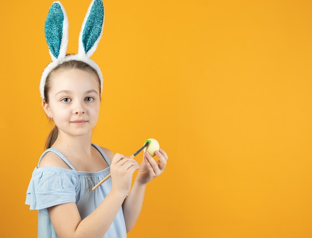 絵画の卵を保持しているウサギの耳を持つ幸せなイースターの子供