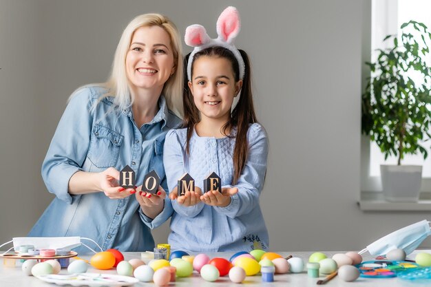 Happy easter. A mother and her daughter painting Easter eggs. Happy family preparing for Easter. Cute little child girl wearing bunny ears on Easter day.