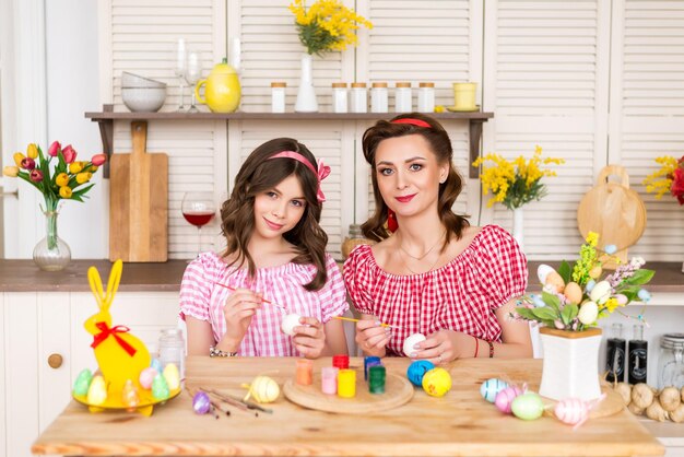 Buona pasqua una madre e sua figlia che dipingono le uova di pasqua famiglia felice che si prepara per la pasqua