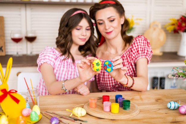 Happy easter A mother and her daughter painting Easter eggs Happy family preparing for Easter