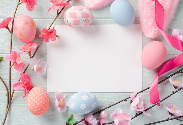 Happy easter, paper card and easter painted eggs in nest on wooden table. Top view with copy space.