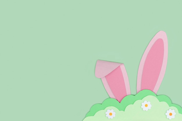 Happy Easter Pink Bunny rabbit ears hide in grass made of green paper on green background