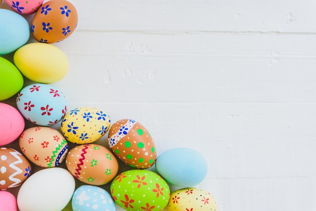 Buona pasqua! file le uova di pasqua variopinte su fondo di legno bianco.