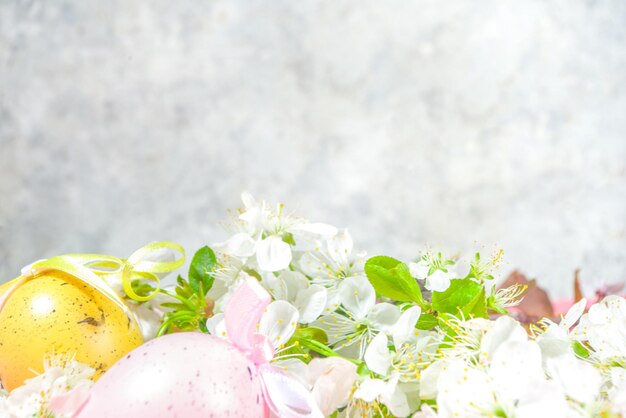 Happy Easter Spring Holiday Greeting Card Background with Easter colorful eggs, decorative bird nests and blossom spring garden flowers, flatlay copy space on high-colored pink background