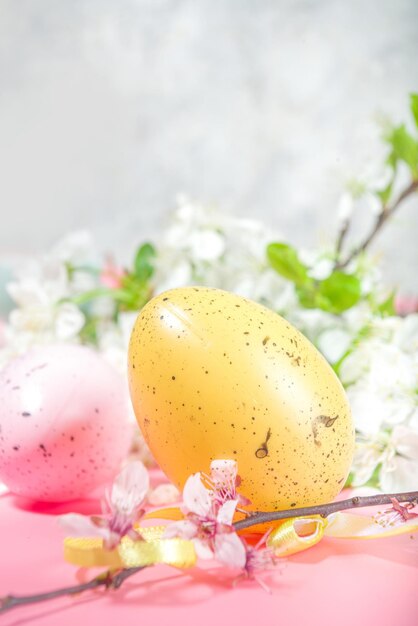 Happy Easter Spring Holiday Greeting Card Background with Easter colorful eggs decorative bird nests and blossom spring garden flowers flatlay copy space on highcolored pink background