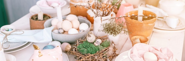 Happy easter and spring holidays time festive tablescape set decor traditional dinner easter eggs and baked cakes on table at home rabbit and willow pale pop pastel blue pink color banner flare