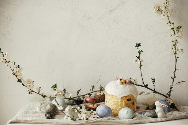 Happy Easter Stylish easter eggs cake bunnies cherry blossom on rustic table Modern natural dyed eggs holiday food and spring flowers Easter countryside still life