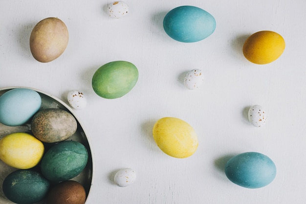 Happy Easter Stylish Easter eggs in plate on rustic white wooden background flat lay