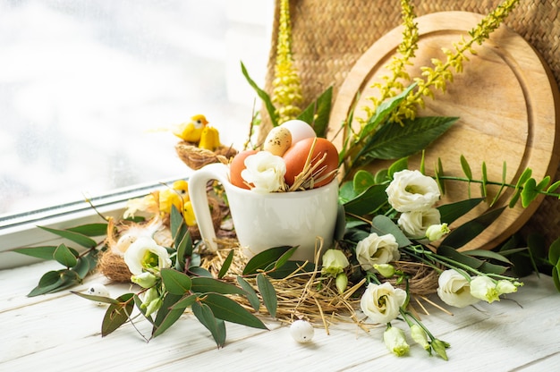 Happy Easter table. Easter egg in a nest with floral decoration near the window. Quail eggs. Happy Easter concept