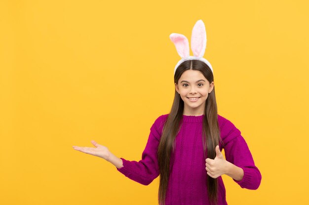 Happy easter teen girl in funny bunny ears presenting product copy space happy easter