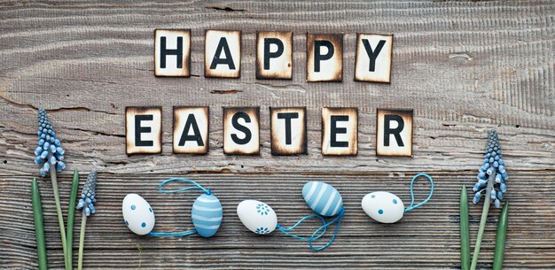 Happy Easter text on rustic wood with blue hyacinth flowers and Easter eggs