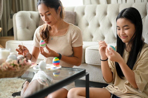 행복 한 가족 개념으로 행복 한 부활절 부활절 달걀을 함께 준비 하는 두 아시아 예쁜 자매