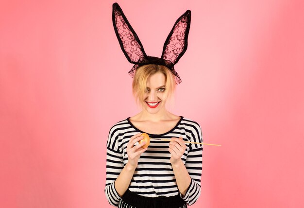 happy easter. woman in bunny ears painting egg, funny rabbit. spring holidays.
