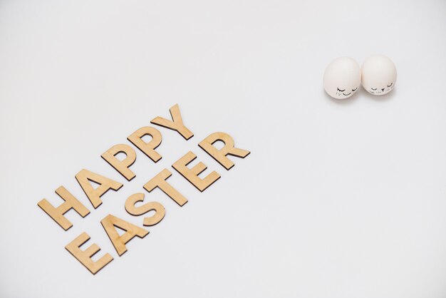 Happy easter in wooden letters with white decorated eggs