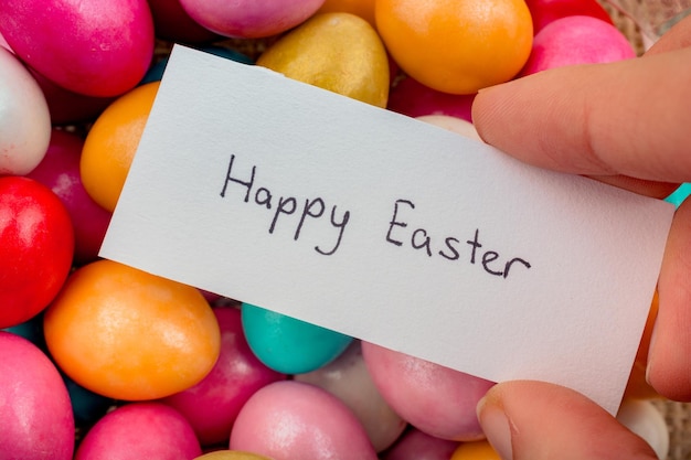 Happy Easter written on a small piece of paper on colorful decorative rocks