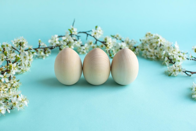 Happy Easter zero waste concept Easter wood eggs with natural decor and fresh flowers Christian religious Easter holiday on a blue background