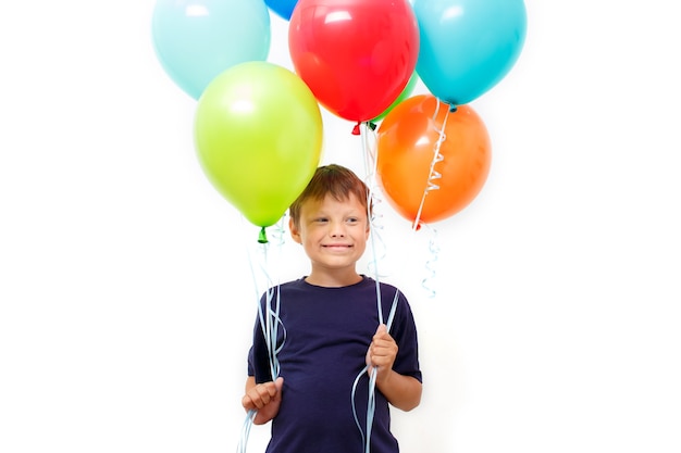 明るいカラフルな風船の腕を持つ幸せな8歳の男の子は誕生日を祝います