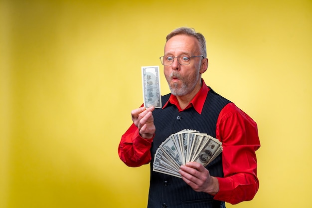 Happy elderly business man with fan of dollar bills