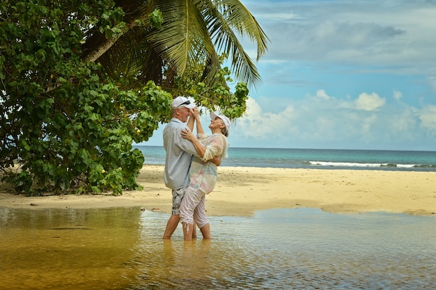 Happy elderly couple dancing at tropical beach