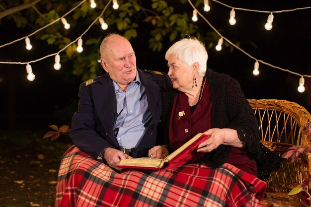 Happy elderly couple in the Park, grandma and grandpa. Look at the photo album.