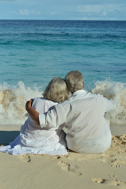 Фото Счастливая пожилая пара отдыхает на тропическом пляже, вид сзади