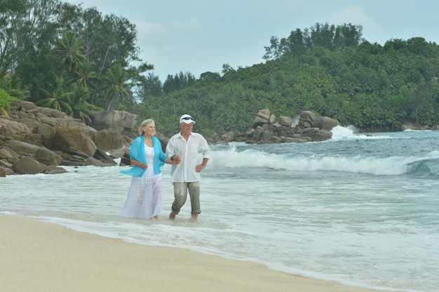 Happy elderly couple running  on tropical  beach