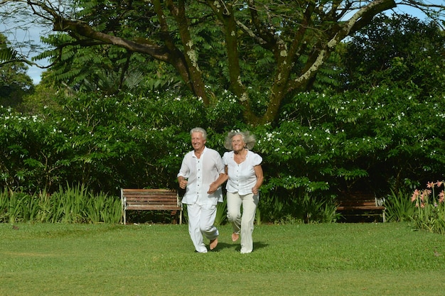 Happy elderly couple running  in tropical garden outdoor