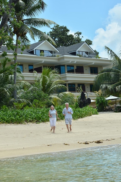 Happy elderly couple on tropical beach running