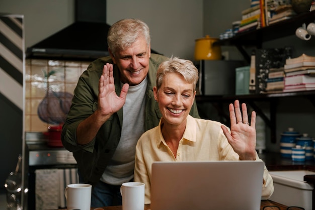 happy elderly couple waving while engaging in video call